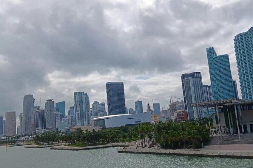 A city skyline with modern high-rise buildings, a body of water, and a park area with trees. 2
