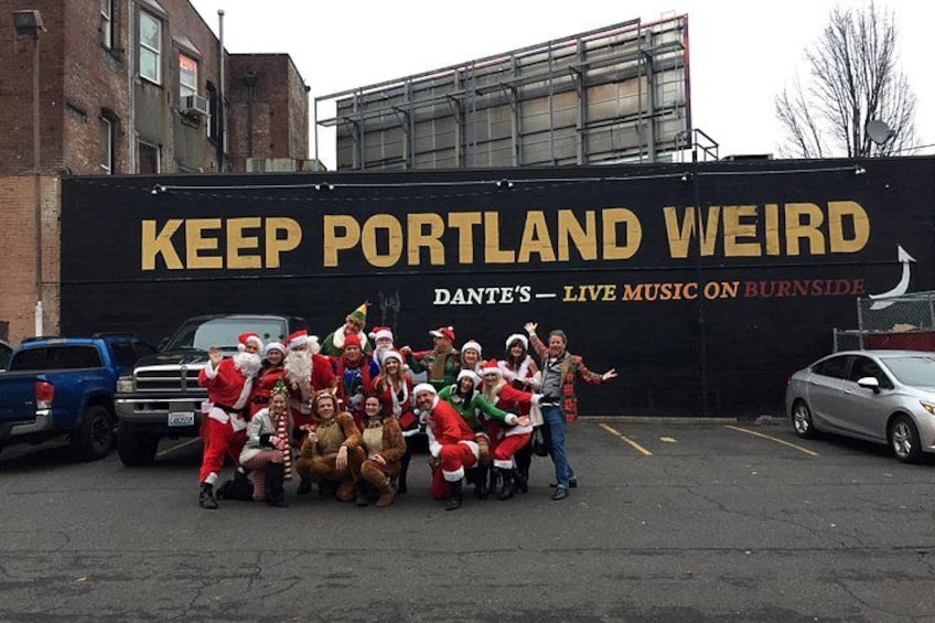 A group of people in festive attire posing in front of a wall with text. 2