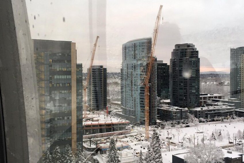 A cityscape with high-rise buildings, construction cranes, and a snowy landscape. 3