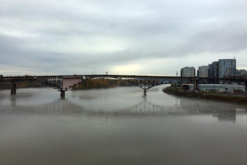A river with a bridge, buildings, and a cloudy sky. 5