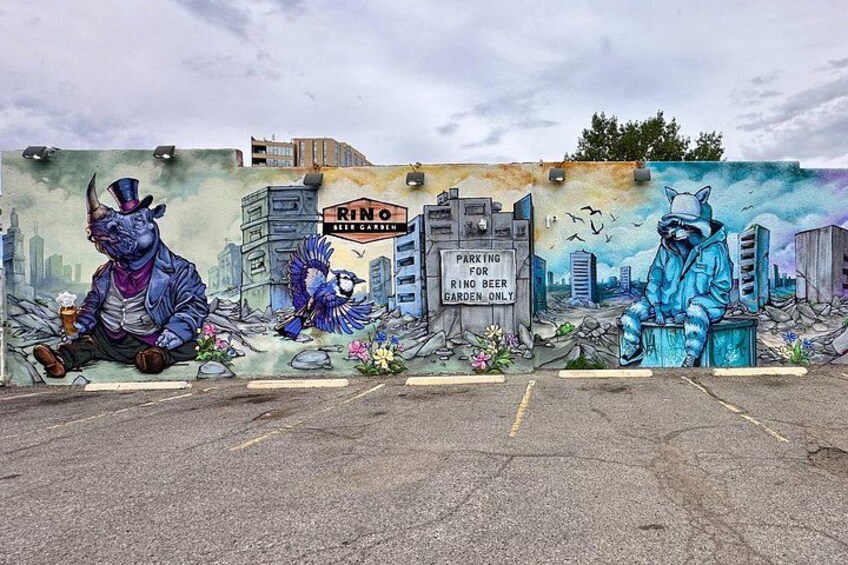 Un mural con un rinoceronte, un gato y un paisaje urbano. 4