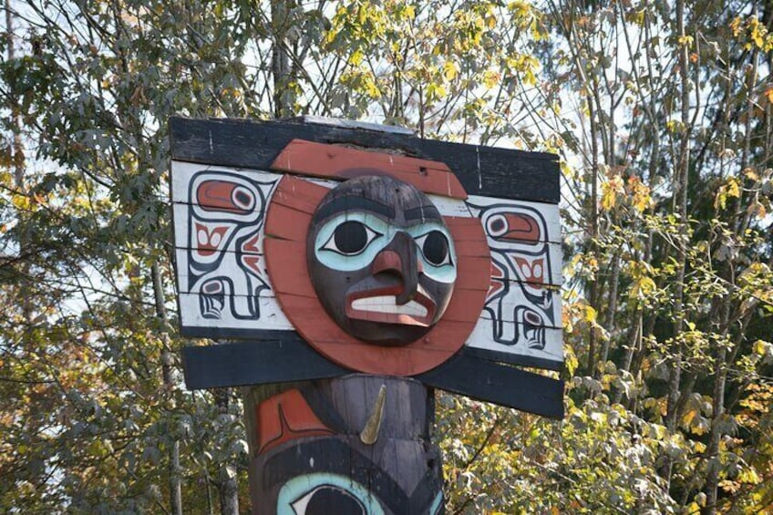 A totem pole with a carved face and painted symbols. 2