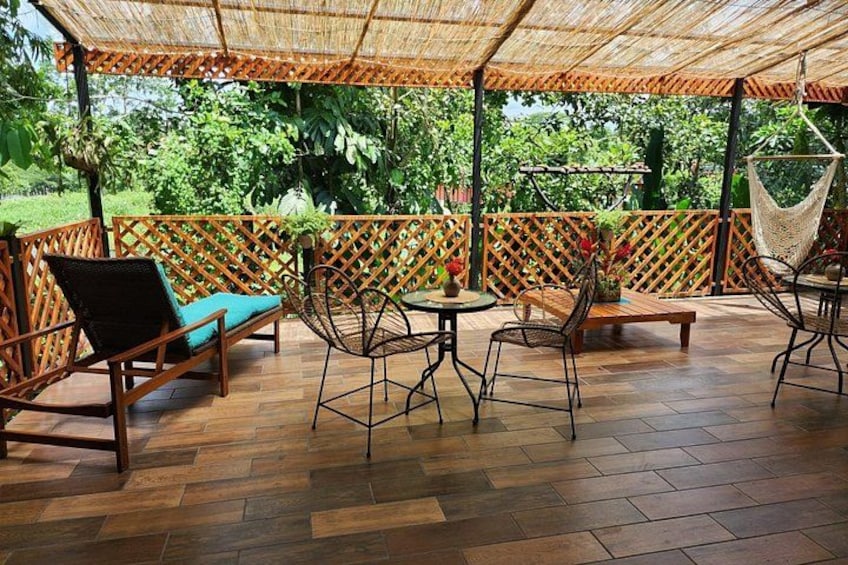 An outdoor patio with wooden furniture, a hanging hammock, and a thatched roof. 4
