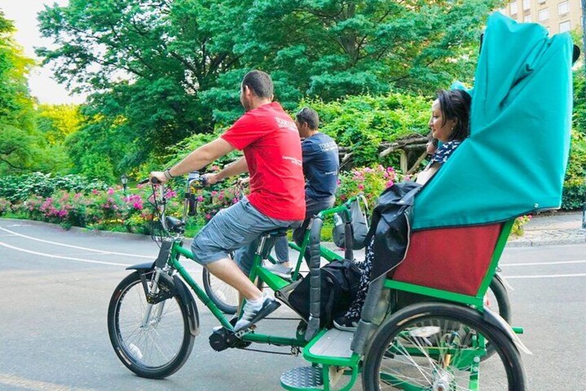 En person som cyklar på en grön cykel och har en passagerare sittande på ett rött säte. 2