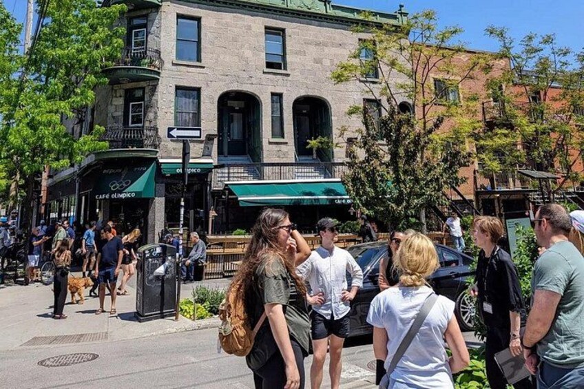Una calle concurrida con peatones, un café y un edificio histórico. 1