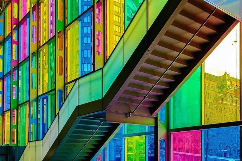 A staircase with colorful panels and a view of a building in the background. 2