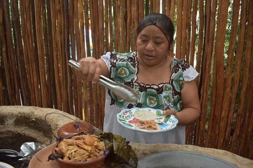 A person serving food from a large clay pot. 3