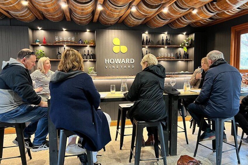 A group of people seated at tables in a restaurant with a wine bar in the background. 5