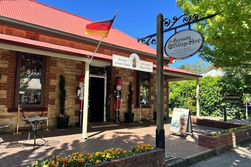 A brick building with a red roof, a German flag, and a sign for 'The German Village Shop'. 2