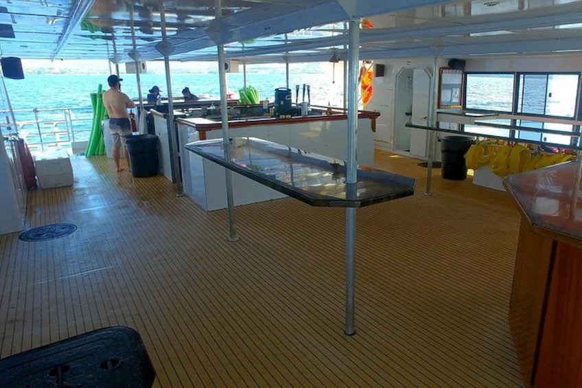 A ship's deck with a table, chairs, and a person standing by the railing. 3