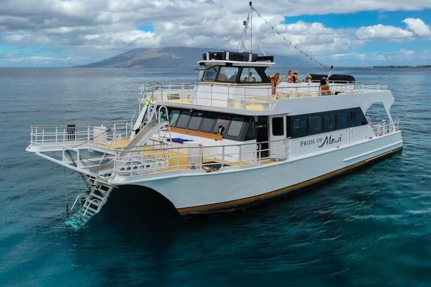 A white boat named 'PRIDE OF MAUI' on calm waters with a mountainous backdrop. 2