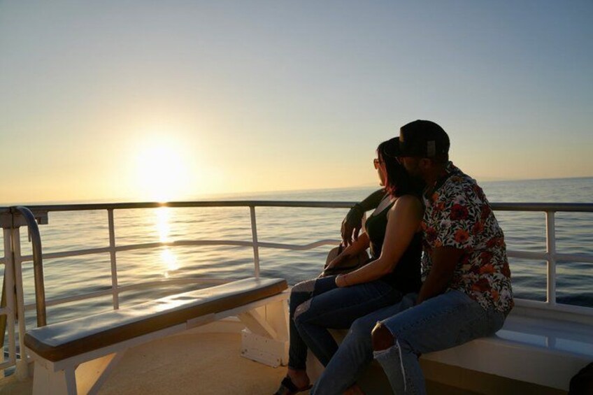 A couple sitting on a bench overlooking the ocean at sunset. 2