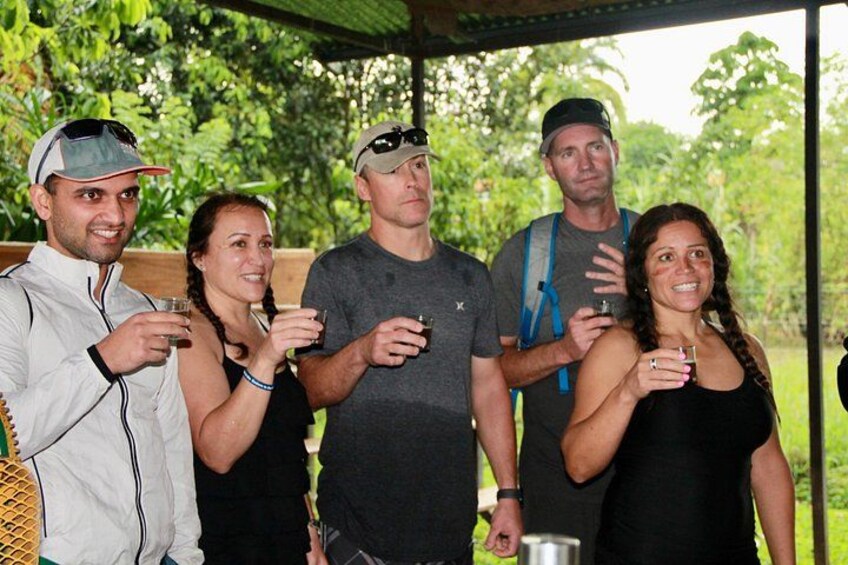Un grupo de personas al aire libre, sosteniendo bebidas, con follaje en el fondo. 2
