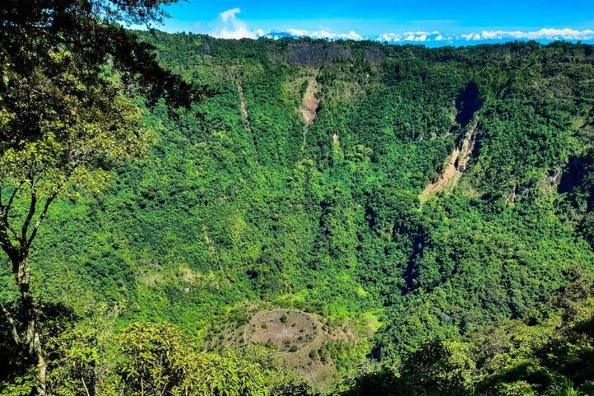 A dense forested mountain landscape with visible ridges and a clear sky. 3