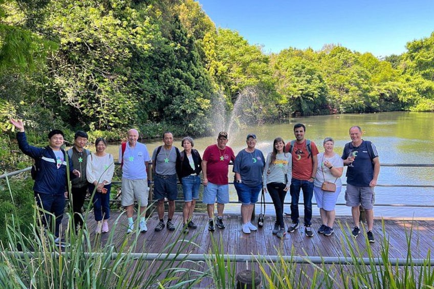 A group of people standing on a wooden bridge over a river, surrounded by greenery. 3