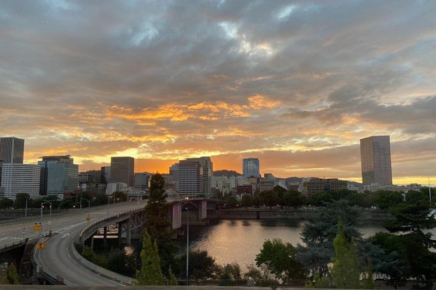 A city skyline at sunset with a river and a bridge. 3