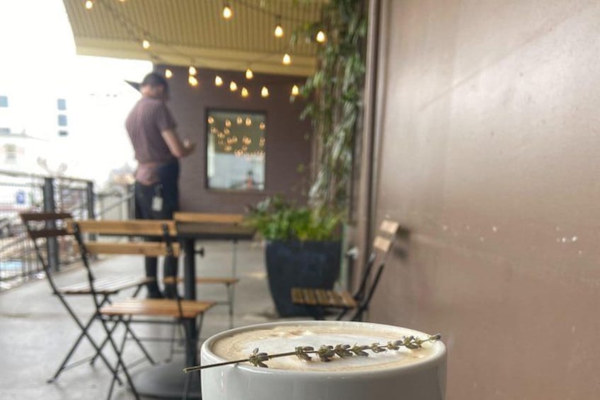 A café with outdoor seating, a person standing, and a plant in the foreground. 3