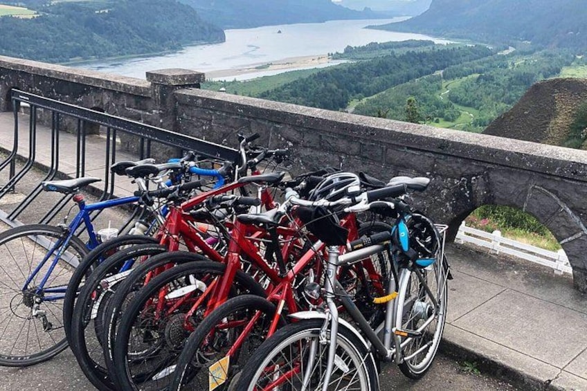 Varias bicicletas están estacionadas en un borde de piedra con vistas a un valle pintoresco. 4