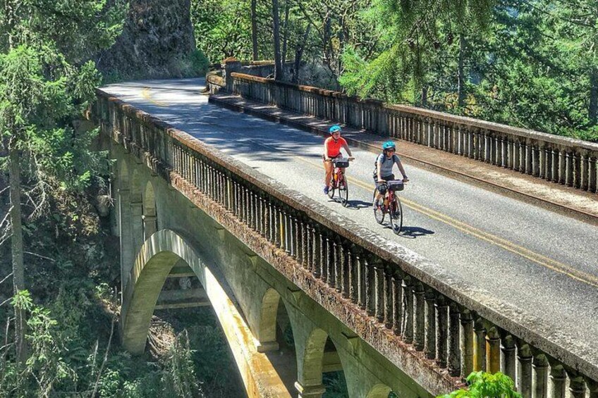 Een stenen brug waarop twee fietsers rijden. 5