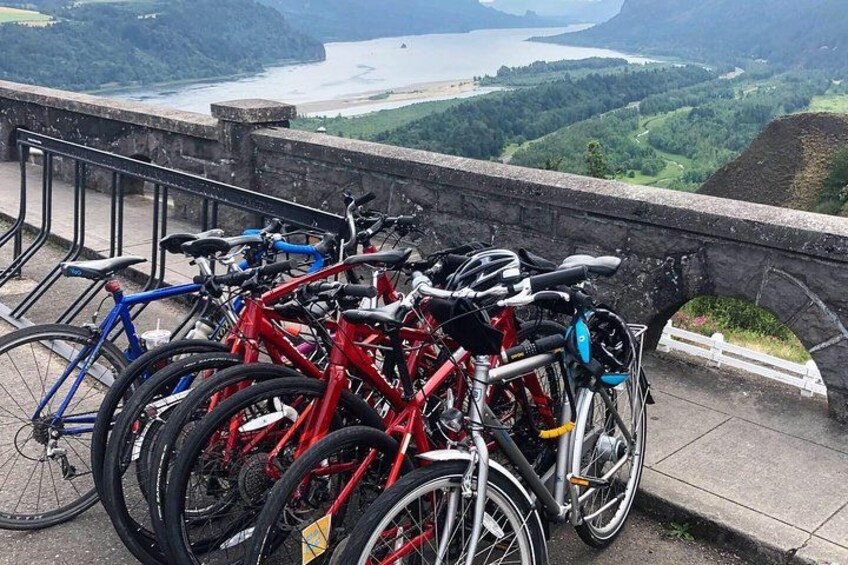Fietsen geparkeerd op een stenen muurtje met uitzicht op een meer en heuvels. 4