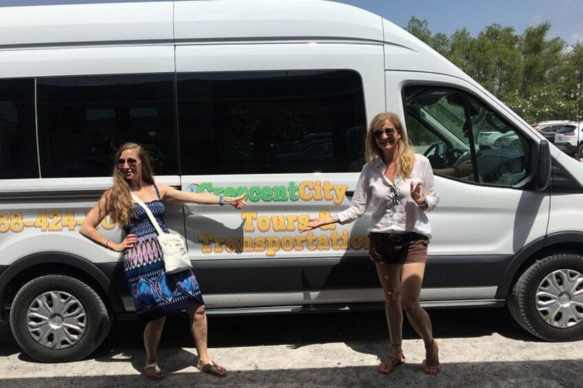 Two women standing next to a white van with 'Crescent City Tours Transportation' written on it. 2