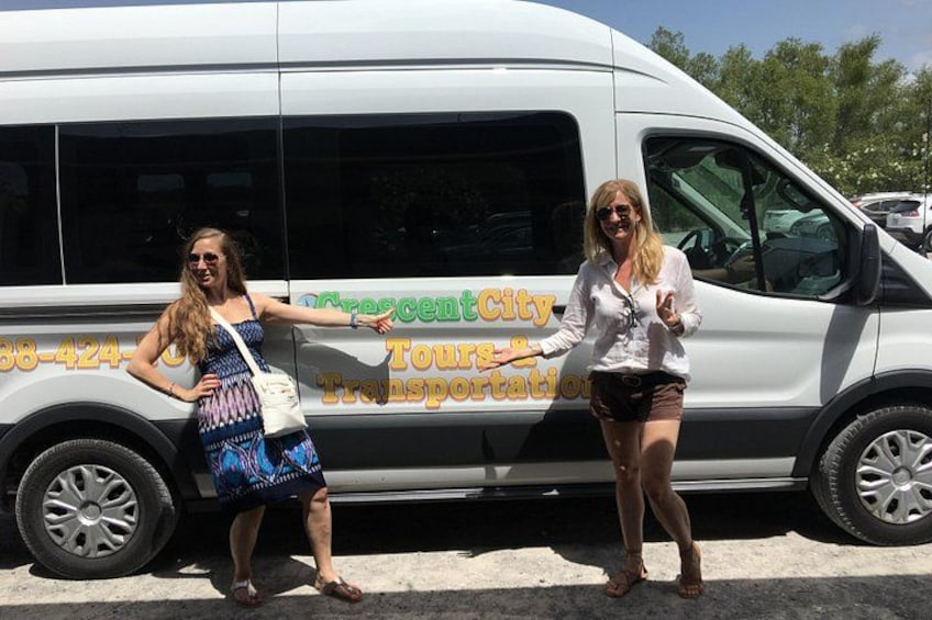 Two people standing next to a white van with 'Crescent City Tours Transportation' written on it. 2