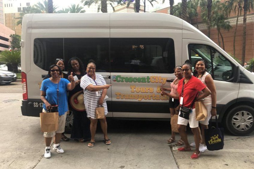 A group of people standing in front of a white van with 'Crescent City Tours & Transportation' written on it. 2