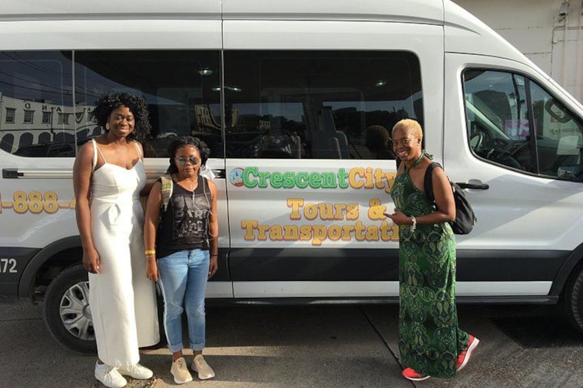 Three people standing in front of a white van with 'Crescent City Tours & Transportation' written on it. 4