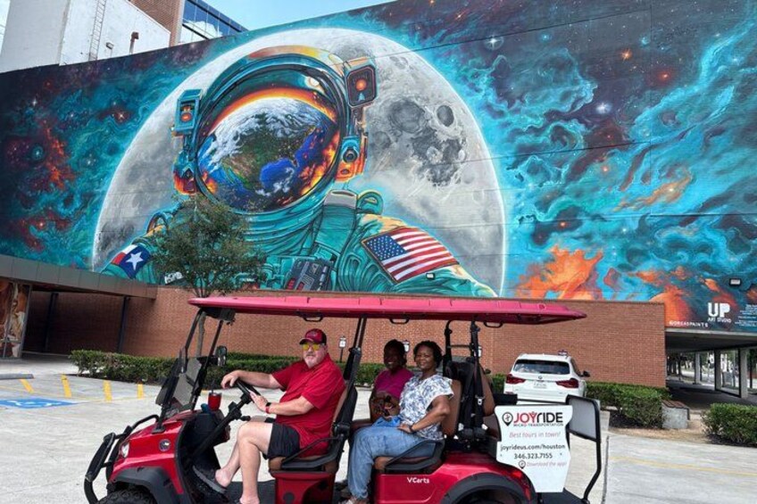 Un carrito de golf rojo con un mural de un astronauta y la luna de fondo. 2