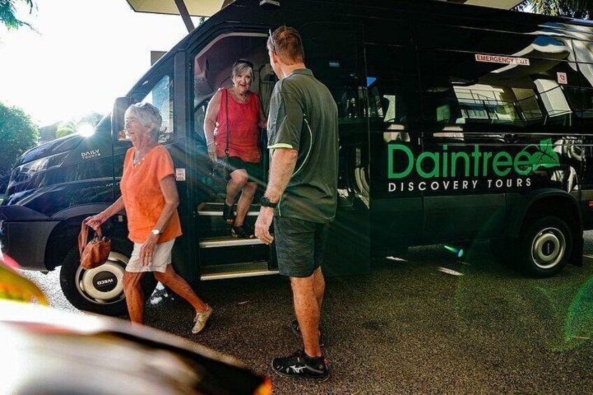 En svart skåpbil med texten ”Daintree Discovery Tours” på sidan, folk som stiger ur bilen och en skylt med texten ”Dairy” på sidan. 2