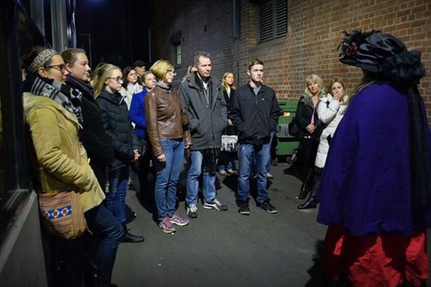 A group of people standing in a line on a street at night. 2