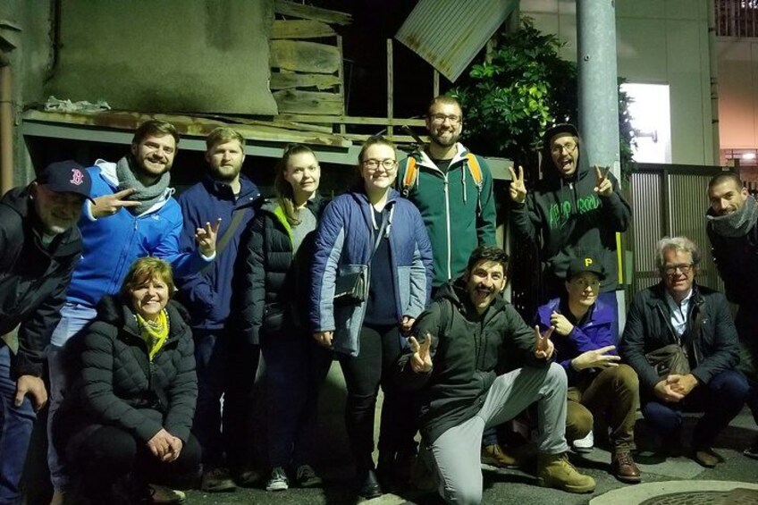 A group of people posing for a photo in an urban setting at night. 1