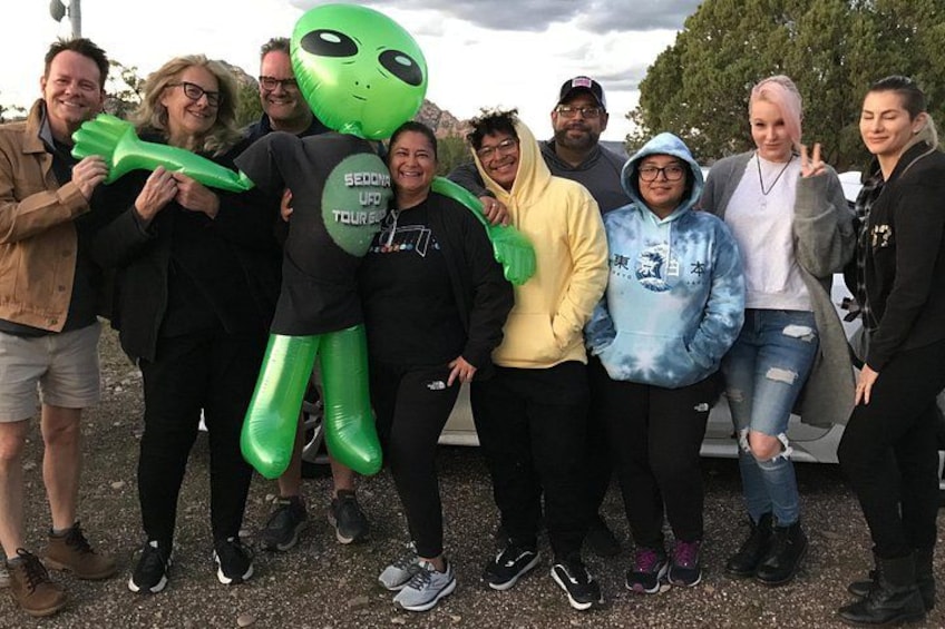 Un grupo de personas posando con un extraterrestre inflable verde y un OVNI inflable negro. 2