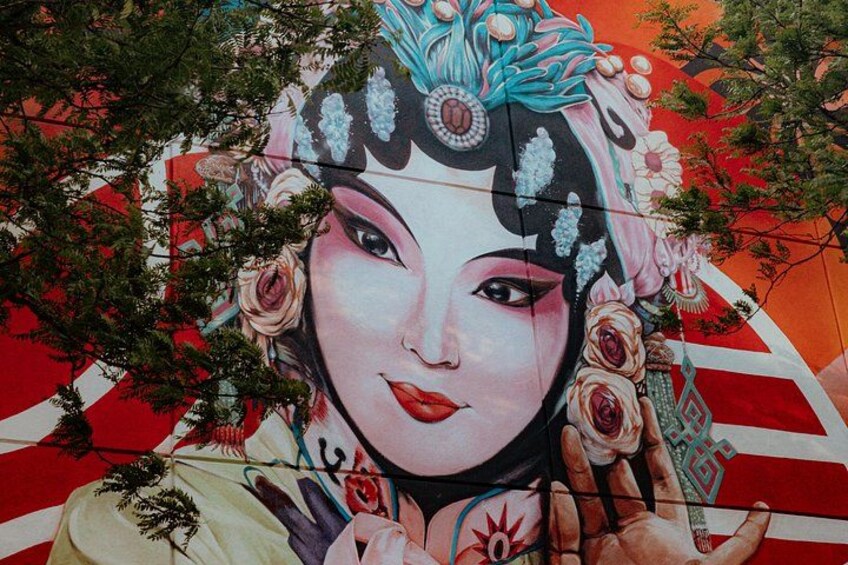 Et mural med en person i traditionelt tøj, omgivet af blomstermønstre og en rød og hvid baggrund. 2