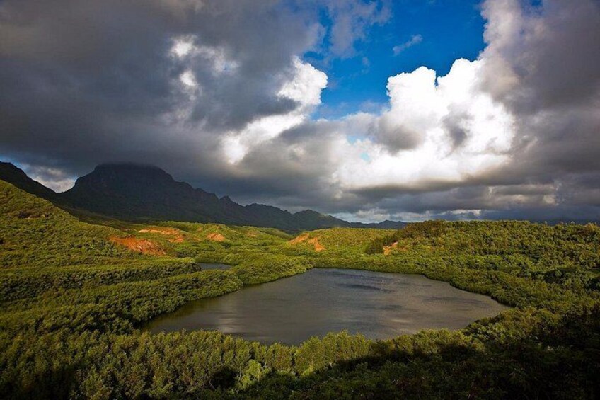 A lake surrounded by green hills and mountains under a cloudy sky. 4