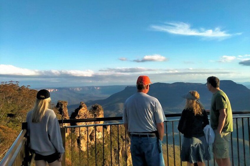 A group of people standing on a railing overlooking a mountainous landscape. 2