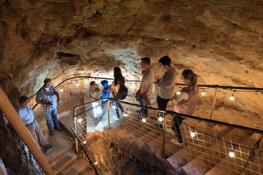 A group of people inside a cave with a staircase and string lights. 2