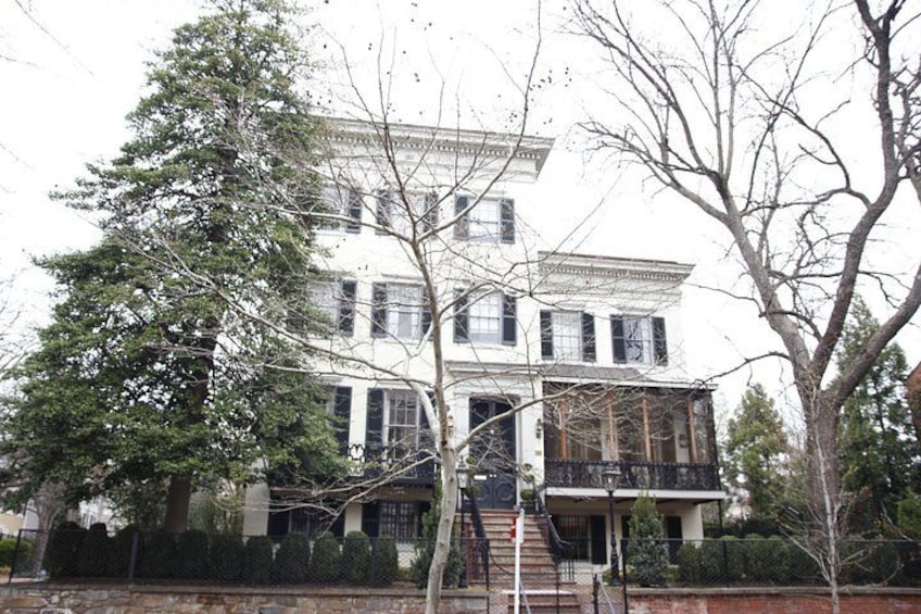 A large, historic building with a symmetrical facade, a central entrance, and a balcony. 2