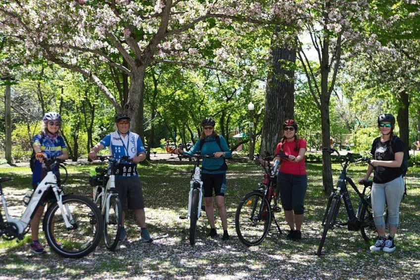 Eine Gruppe von Menschen mit Fahrrädern in einem Park mit Bäumen. 2