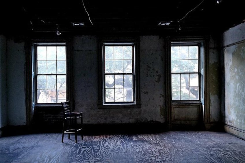 A room with three windows, a wooden chair, and a patterned floor. 2