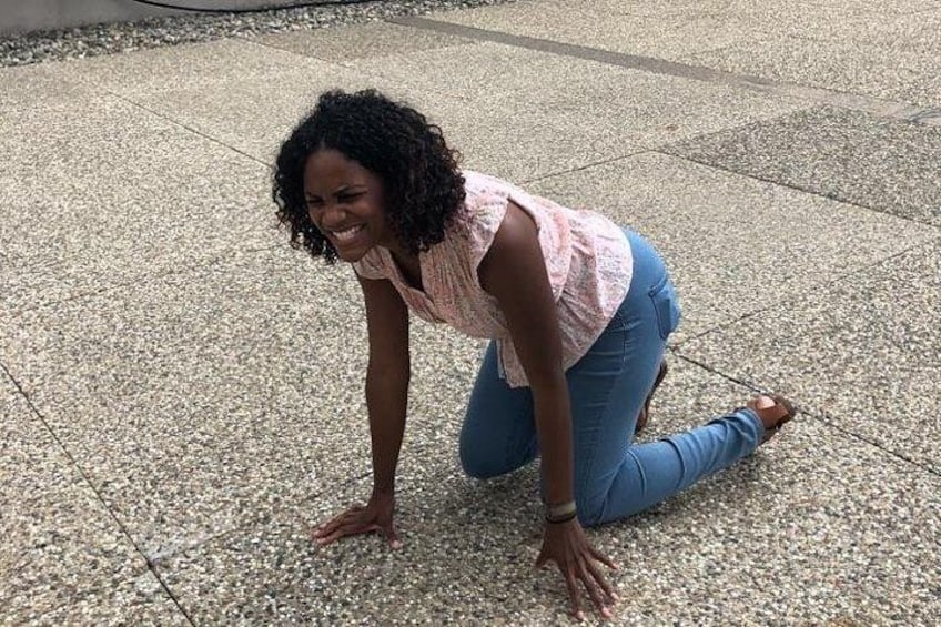 A person kneeling on a textured pavement surface. 1