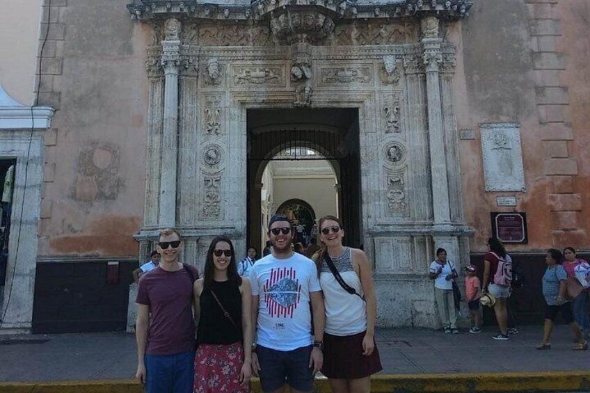 Un grupo de personas frente a un edificio histórico ornamentado, con intrincados grabados y un gran arco. 2
