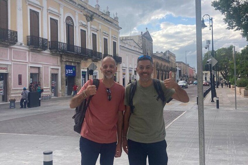 Two people standing on a city street with historic buildings in the background. 2