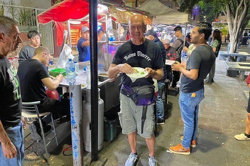 Un vendedor ambulante de comida atendiendo a clientes por la noche. 5