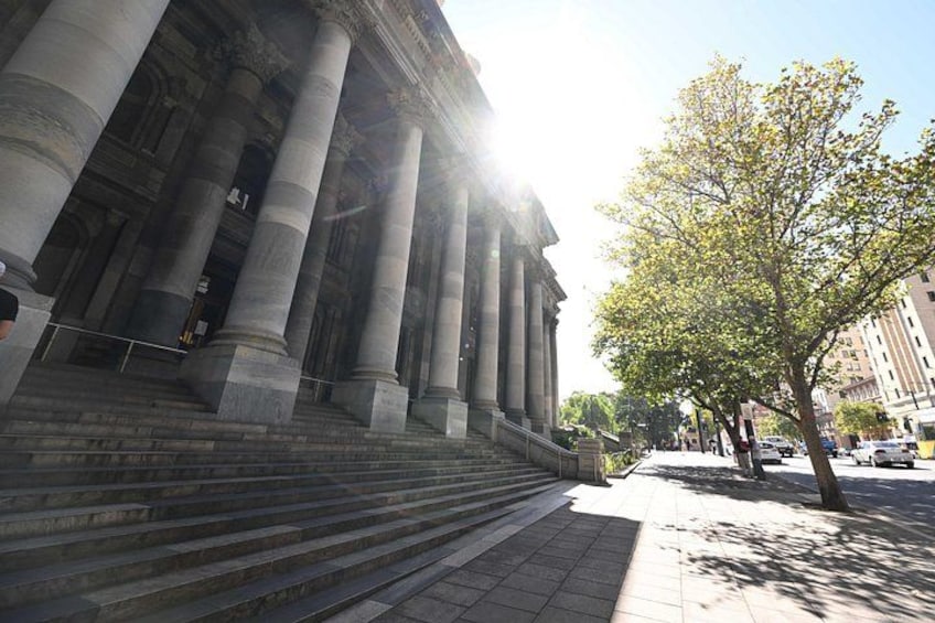A grand building with large columns, steps leading up to it, and a tree-lined sidewalk. 3