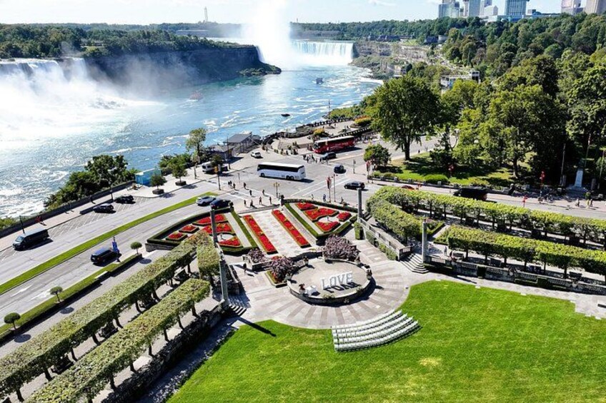 A landscaped area with a central fountain, a waterfall in the background, and a cityscape. 5