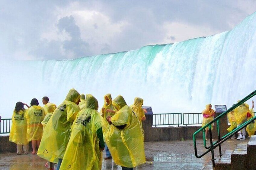 People in yellow rain ponchos standing by a large waterfall. 1