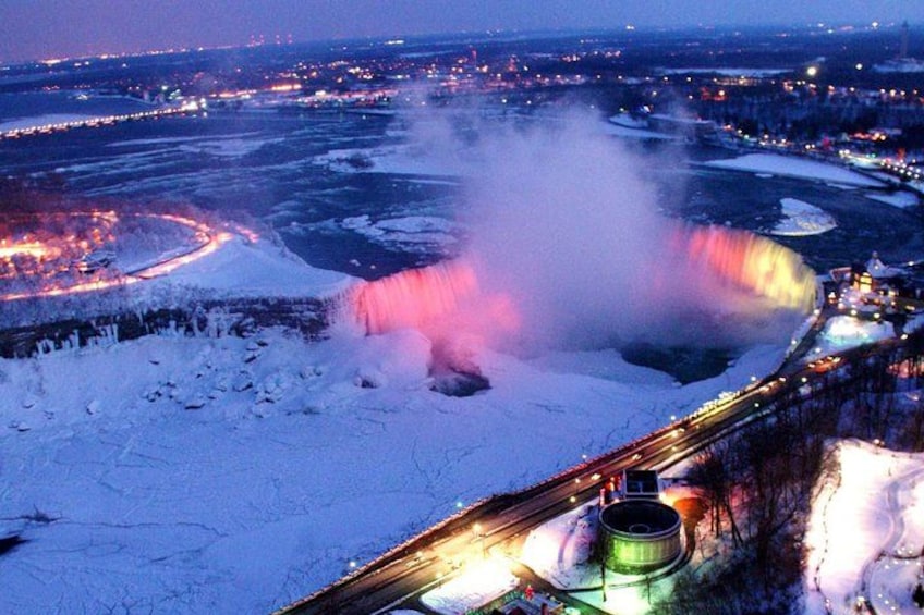 Un paysage enneigé avec une cascade et une voie ferrée illuminée. 1