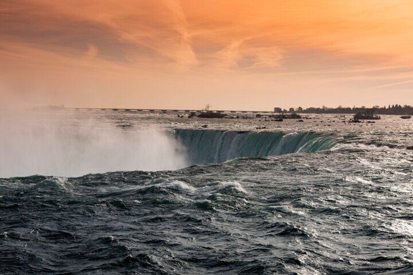 A waterfall at sunset with a city skyline in the background. 1