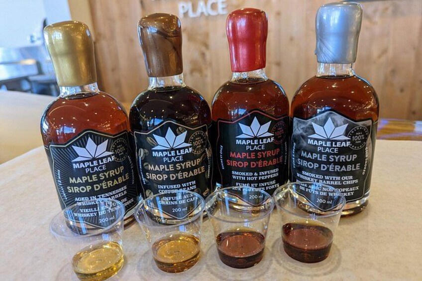Quatre bouteilles de sirop d’érable, avec leurs étiquettes, et deux petits récipients en verre contenant du sirop. 5